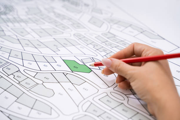 istock Human Hand Holding Pencil Over Cadastre Map 1184243109