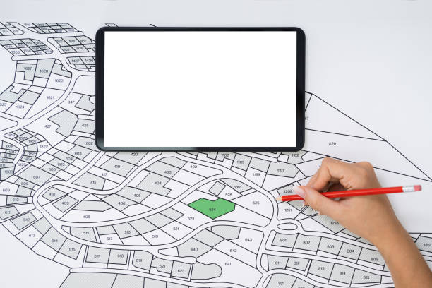 istock Human Hand Holding Pencil Over Cadastre Map 1184243121