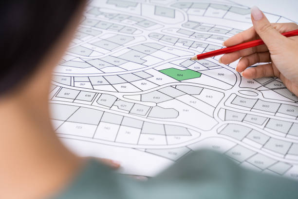 istock Human Hand Holding Pencil Over Cadastre Map 1184243137