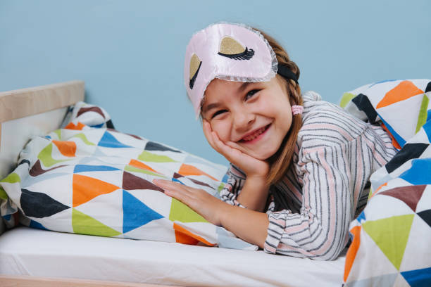 istock Cute little girl lying in bed with a sleeping mask on her forehead 1184244876