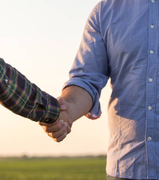 Two farmers shaking hands in field