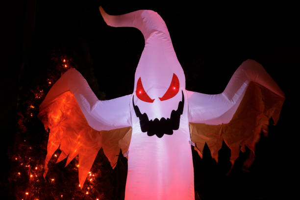 Inflatable Winged Ghost Glowing in the Dark for Halloween Spirit. Blow up ghost decorating home exterior. blow up doll stock pictures, royalty-free photos & images