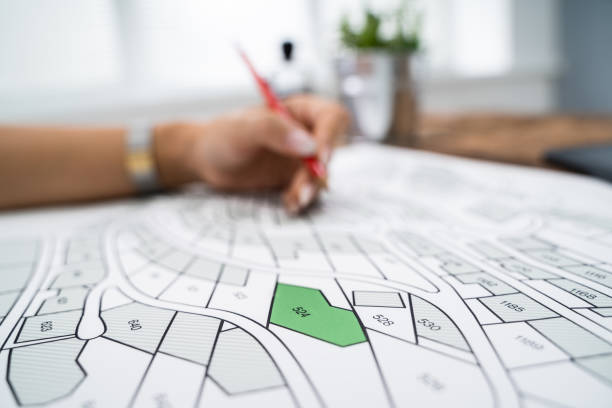 istock Human Hand Holding Pencil Over Cadastre Map 1184249912