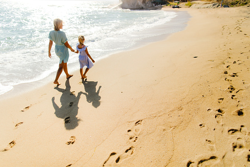 Photo of mother and daughter enjoying in a walk by the sea