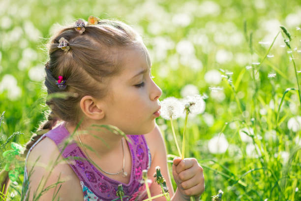 istock Girl blowing dandelions on medow 1184251187