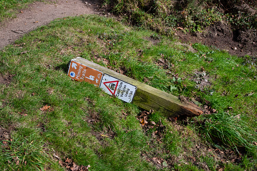 A knocked down 'caution - vehicles' sign on the side on a rural track
