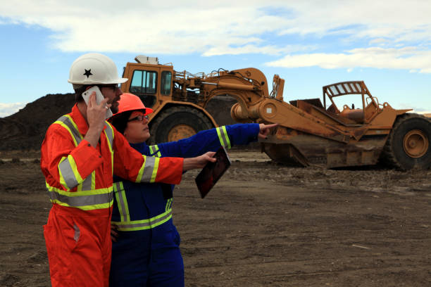 istock Male and Female Construction workers talking on phone and looking at tablet while pointing at work site 1184255893