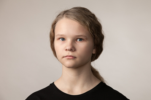 Studio close-up portrait of teenage girl in black t-shirt on beige background
