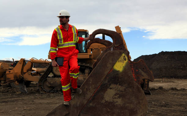 istock Male Construction worker holding a tablet while standing on a vehicle scoop at work site 1184258909