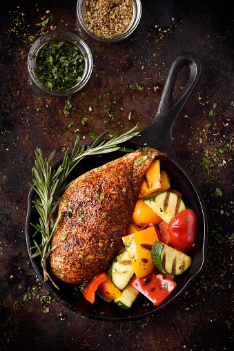 Roast chicken breast with grilled vegetables in a cast iron skillet