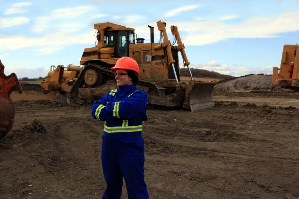 Female Construction worker with arms crossed at work site in front of heavy construction equipment at Cochrane, Alberta, Canada cochrane alberta stock pictures, royalty-free photos & images