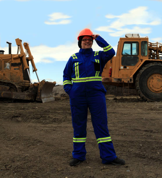 istock Female Construction worker tipping hardhat at work site 1184261850