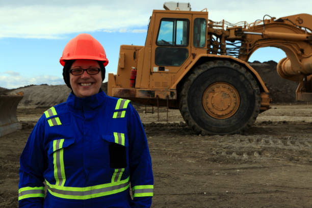 istock Female Construction worker posing in front of earth mover at work site 1184262005