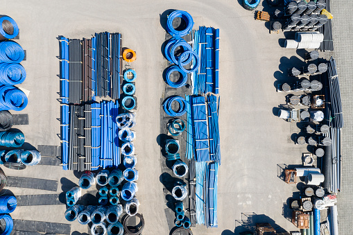 PVC plastic pipes for underground water supply and water meter covers viewed from above at a depot.