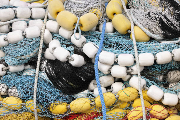 Fishing nets, buoys, floats, ropes and commercial tackle lay in a jumble in this horizontal, full frame, close-up.