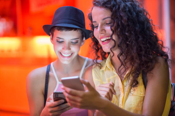 istock Young girlfriends using phone on the street 1184265307