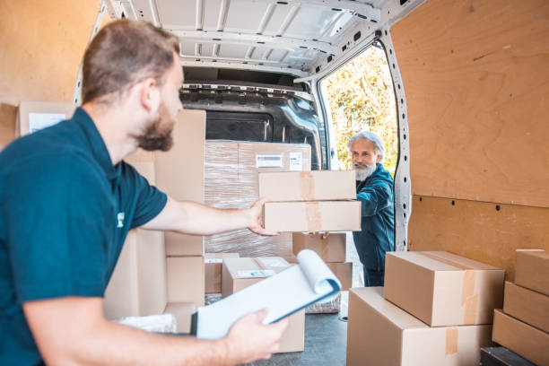 istock Two people unloading the delivery van filled with packages 1184269425
