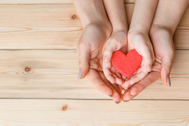 istock hands with red heart on wooden background 1184277231