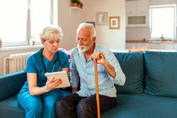 istock Happy senior man and nurse using digital tablet at home 1184277759