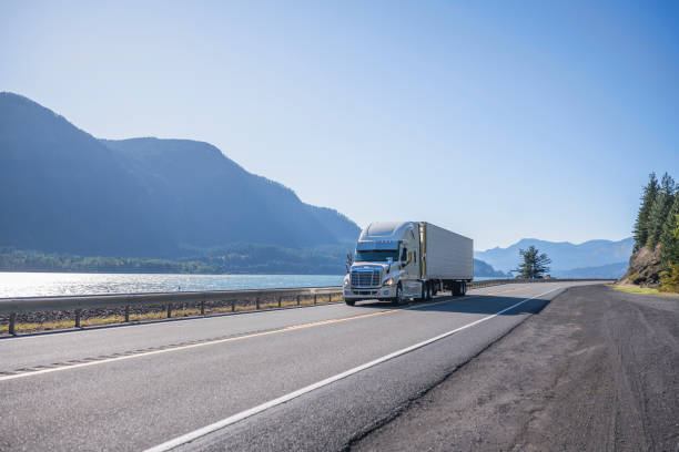 istock Big rig professional popular semi truck tor long haul freight transporting cargo in refrigerator semi trailer running on the road along the Columbia River at sunny day 1184281604
