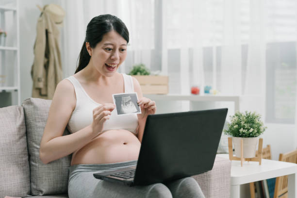 schwangere mädchen auf video anruf zeigen ultraschall foto - human pregnancy telephone ultrasound family stock-fotos und bilder