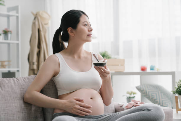 kobieta w ciąży trzymająca słodką zupę w ręku - human pregnancy abdomen naked human hand zdjęcia i obrazy z banku zdjęć