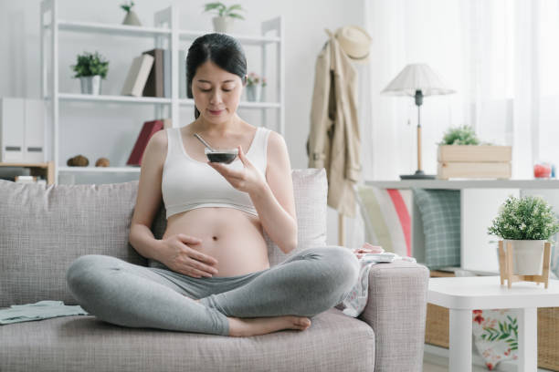 kobieta w ciąży pijąca dania lecznicze w domu - human pregnancy abdomen naked human hand zdjęcia i obrazy z banku zdjęć