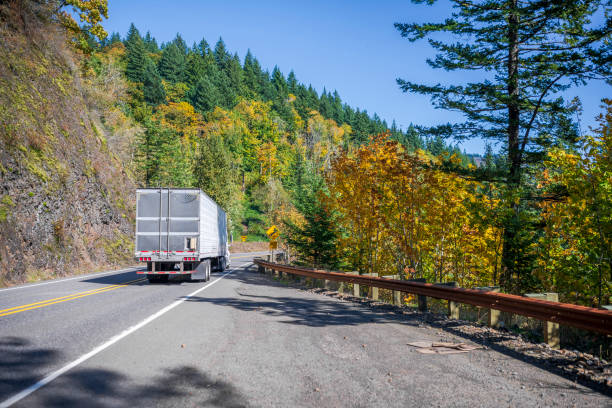istock Big rig sommercial long haul semi truck transporting cargo in refrigerator semi trailer running on the winding autumn mountain road in Columbia Gorge area 1184284813