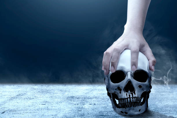 istock Hand holding human skull above the floor 1184285960