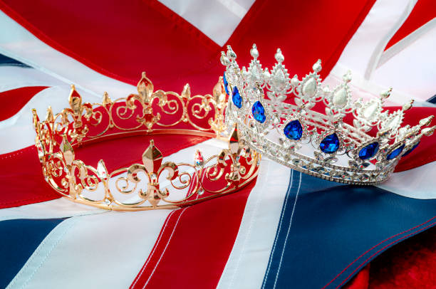 la realeza británica, coronación real y el tema del concepto de monarquía con una corona de rey de oro y una tiara reina de plata con la bandera del reino unido llamada el gato de la unión en el fondo - british flag flag british culture old fashioned fotografías e imágenes de stock