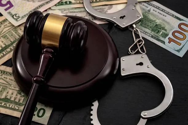 Bail bond system, bailing out of jail and innocent until proven guilty conceptual idea with judge wooden gavel, dollar banknotes and handcuffs