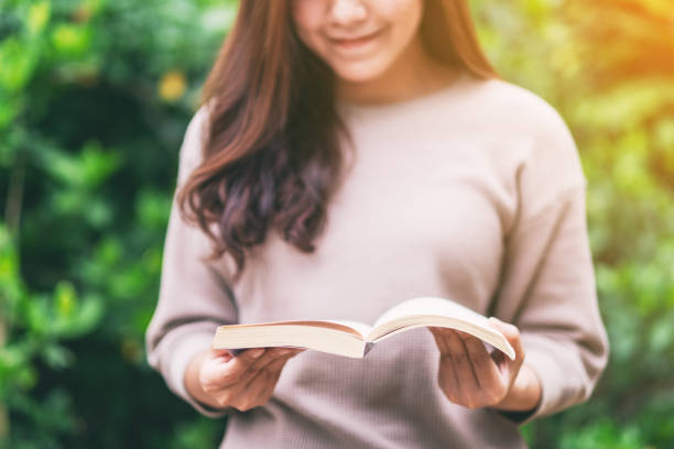 istock woman reading a book while sitting in the park 1184296136