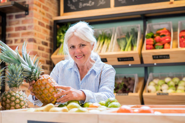 donna anziana al supermercato che compra frutta e verdura - senior adult aging process supermarket shopping foto e immagini stock
