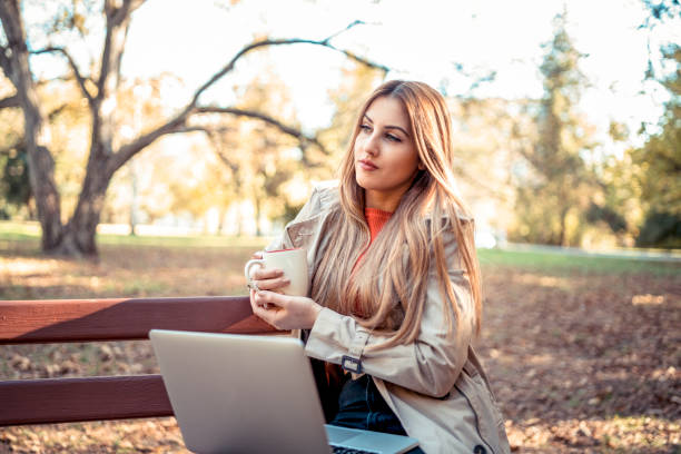 istock Working outdoor sitting on a park bench in fall season 1184301042