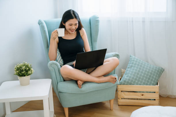 istock laughing girl using notebook with cup of tea 1184302900