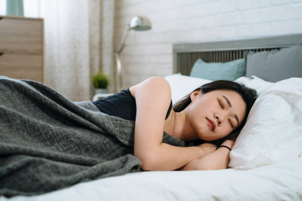 girl has pleasant dreams and health sleep Shot of lovely asian chinese girl has pleasant dreams and health sleep in white bed. young smiling woman having good rest during weekends. Sleeping female in cozy sunny bedroom in morning at home. side eye expression stock pictures, royalty-free photos & images