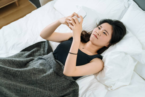istock girl cover with blanket in bed using cellphone. 1184303622