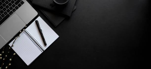 istock Overhead shot of dark modern workspace with laptop computer and open notebook 1184304847