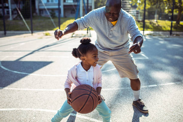 Grandfather and Granddaughter Close up of a grandfather taking his granddaughter to play some basketball in the park making a basket scoring stock pictures, royalty-free photos & images