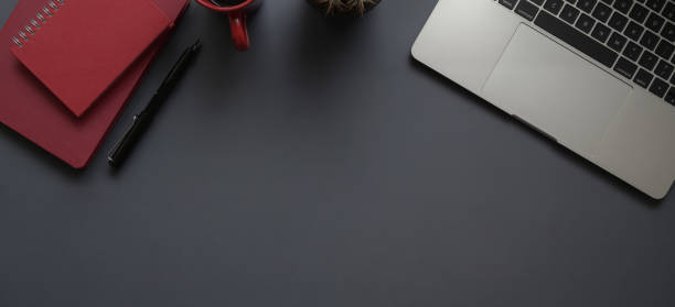 istock Top view of dark modern workplace with laptop computer, office supplies and red notebook with copy space 1184306083