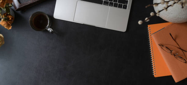 istock Overhead shot of dark modern workspace with laptop computer, orange notebook with office supplies 1184306089