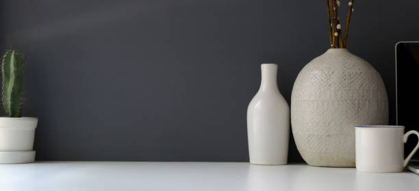 istock Modern workspace with copy space and ceramic vase on white table and grey wall 1184306118