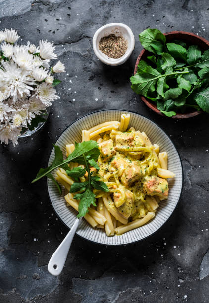 istock Curried creamy salmon with pasta on a dark background, top view 1184307734