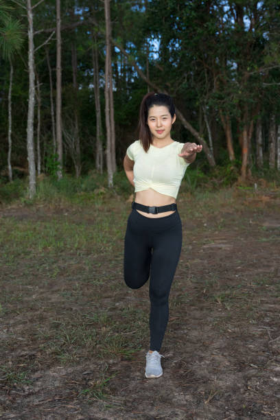 istock Young Asian woman runner does stretching and warm up exercise before trial running in nature forest in the morning. Sporty young female working out in forest. Weight Loss. Health care and lifestyle. 1184307735