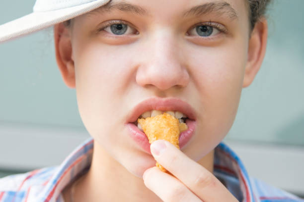 istock girl eats shrimp in batter, front view, close-up 1184307972
