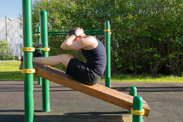 istock man doing abs exercises on an incline bench in a park 1184307974