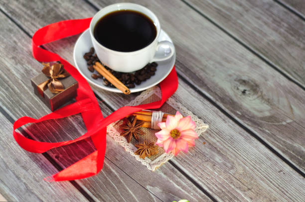 istock A beautiful composition, a cup of black coffee, decorated with grains, anise and korets, is surrounded by a bright red ribbon near the gift box. 1184311995