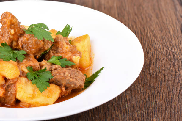 Beef stew with potatoes in a white plate. Close up. Rustic style.
