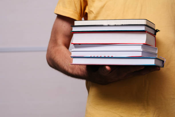 istock a stack of books in the hands of a man 1184319423