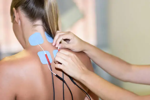 Electro stimulation in physical therapy to a young woman. Medical check at the shoulder in a physiotherapy center.